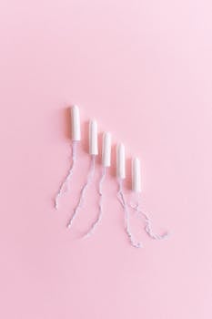 Flat lay of tampons arranged on a pastel pink background, emphasizing feminine hygiene.