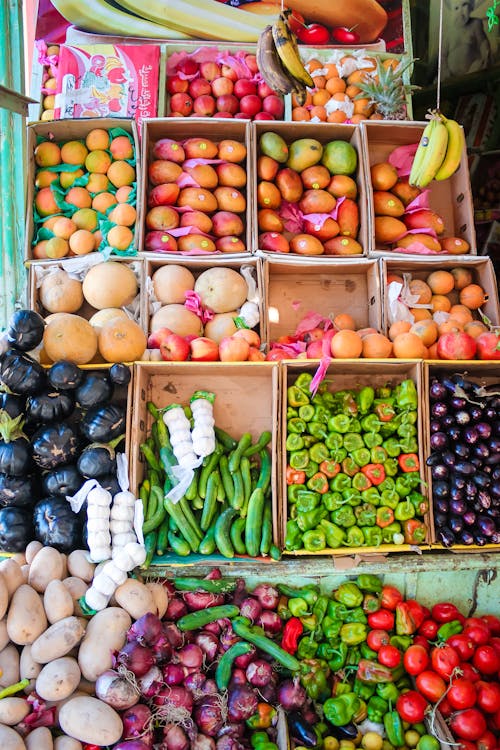 Fresh exotic fruits and vegetables placed on counter in market stall at daytime