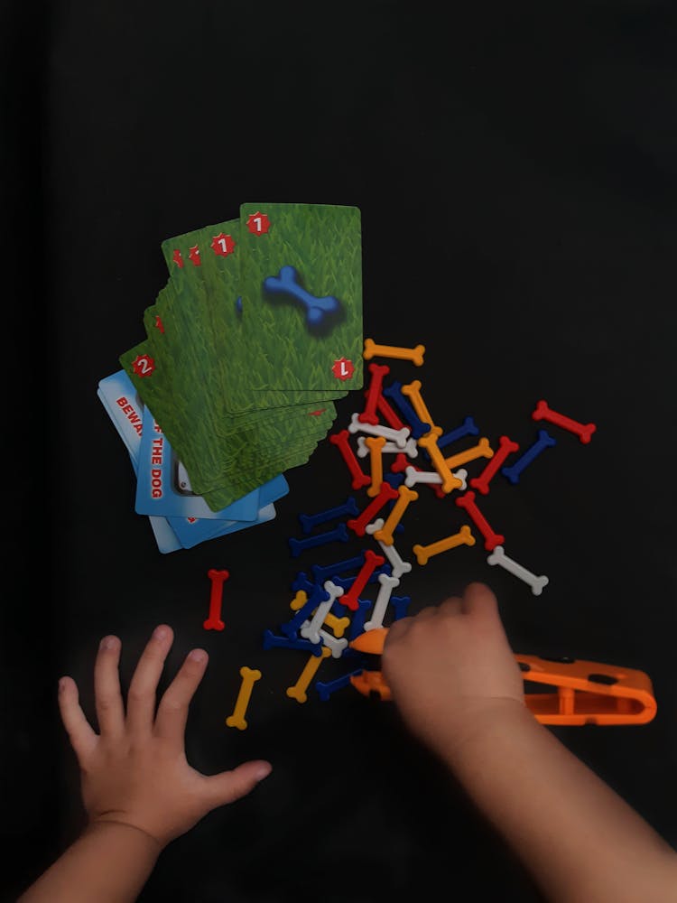 Hands Of Child Playing With Toys Cards And Bones