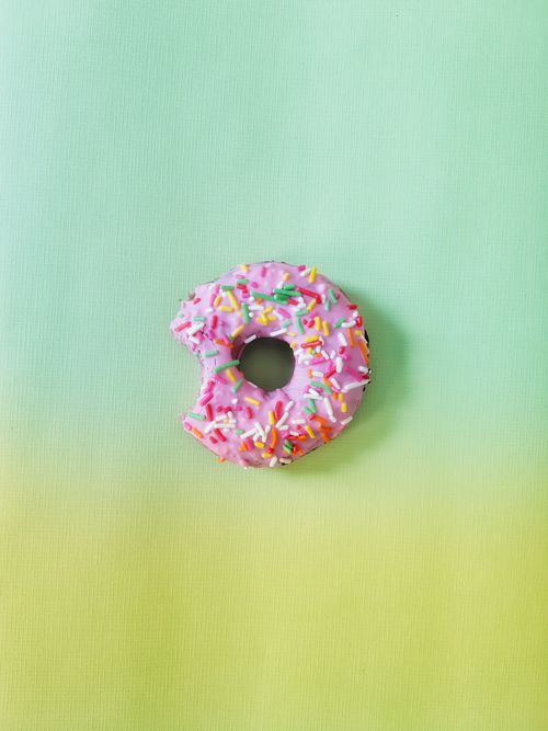 Free A colorful pink donut with sprinkles on a pastel gradient background, top view. Stock Photo