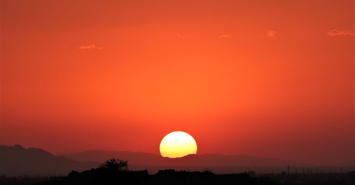 A breathtaking sunset over Phoenix, Arizona desert, showcasing vibrant orange sky and silhouettes of mountains.