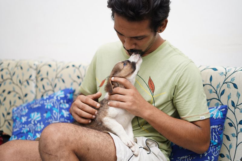 A new pet owner lovingly holding a puppy on the sofa at home