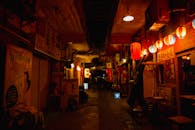 Dark narrow street between shops illuminated by decorative lanterns