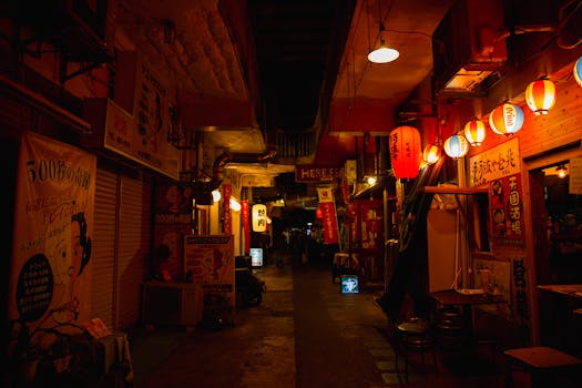 Narrow walkway between street shops with shiny lamps in Asian town at night