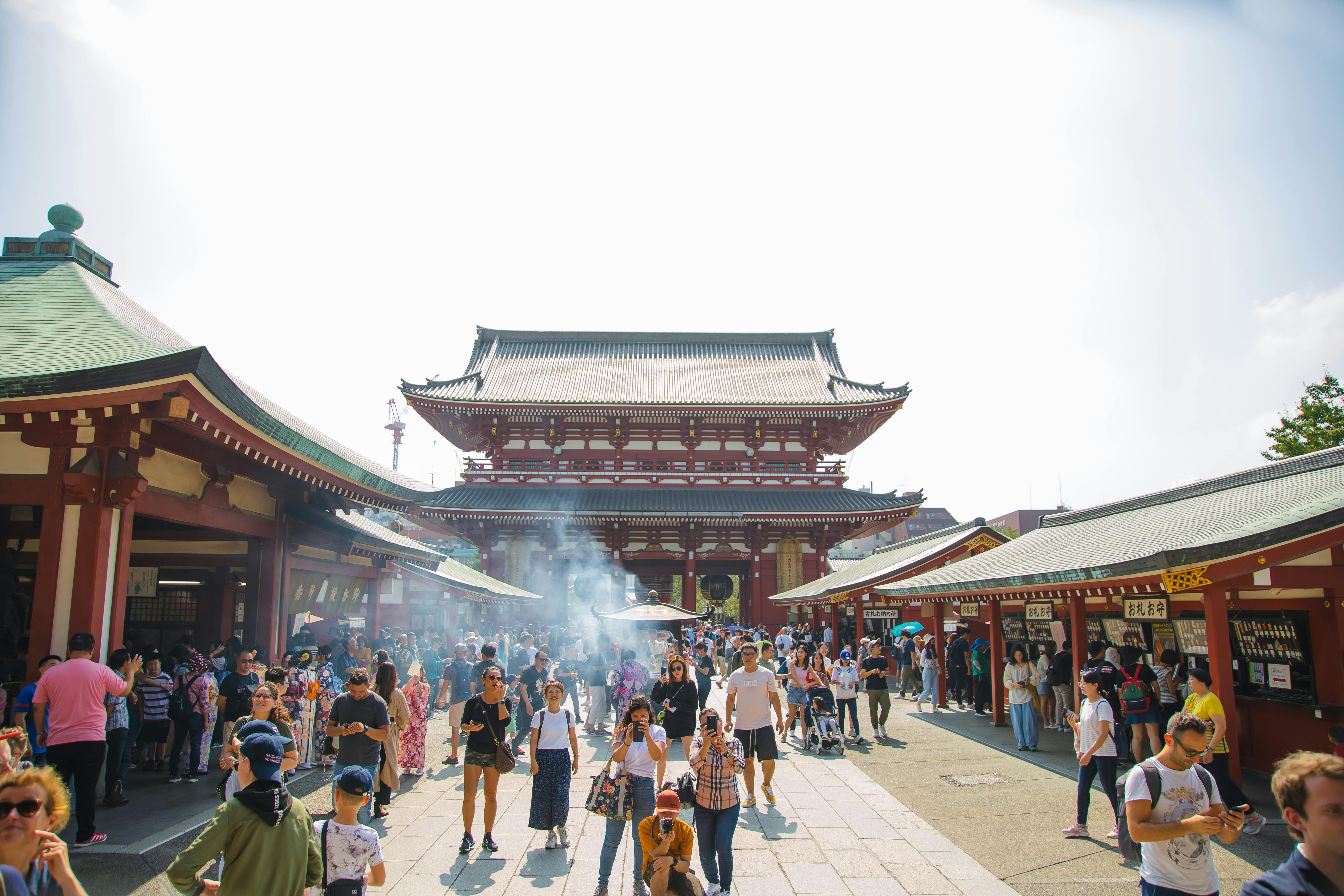 unrecognizable tourists walking near old buddhist temple in city