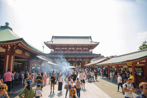 Unrecognizable tourists walking near old Buddhist temple in city