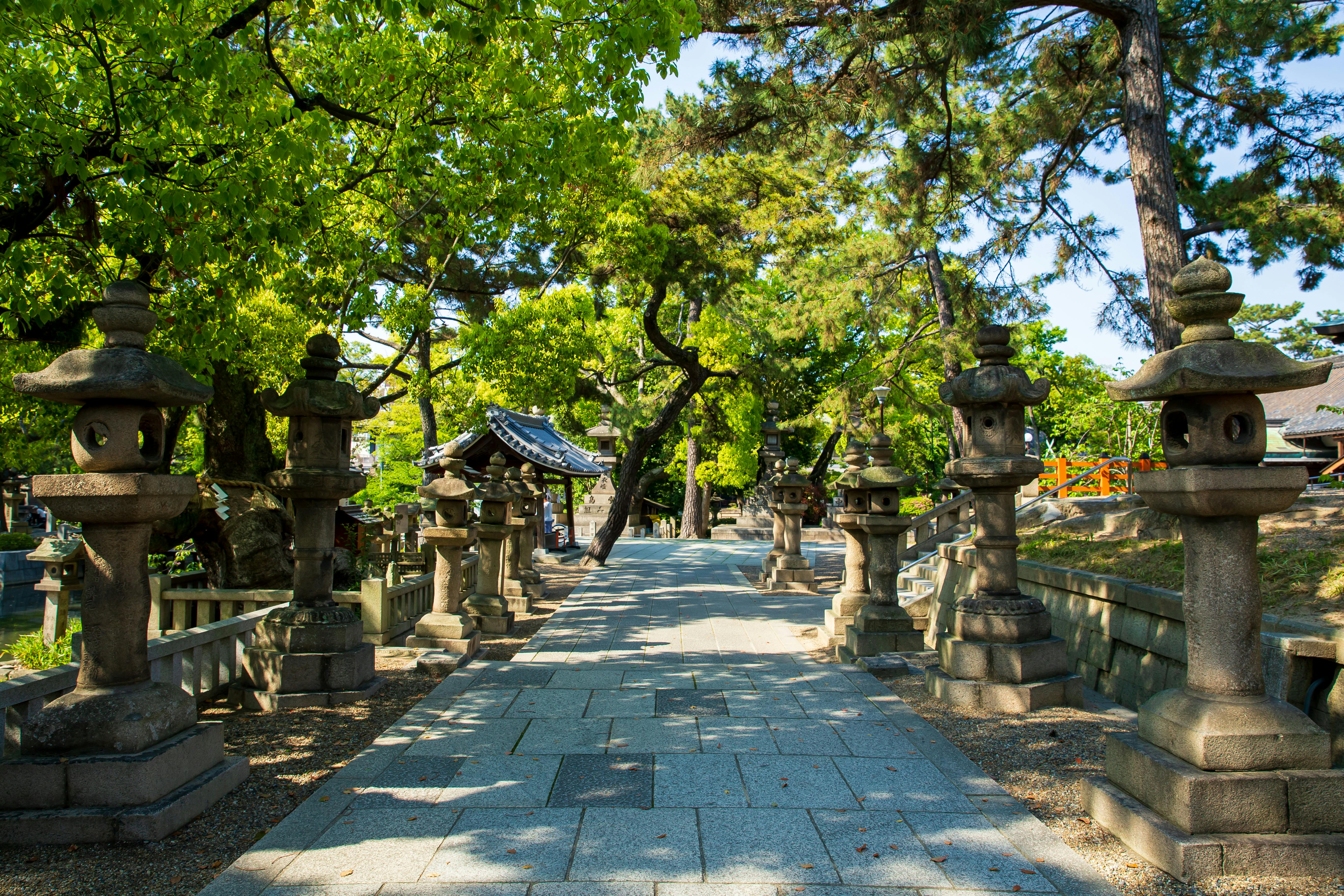 pathway between stone sculptures and trees in city park