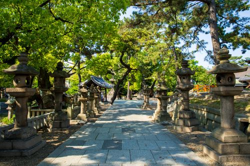 Free Empty tiled walkway between masonry statues and greenery trees in Asian park in daylight Stock Photo