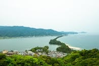 Scenic landscape of sea with sandbar surrounded by hills covered with lush green trees