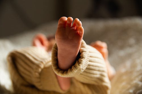 Free Foot of unrecognizable newborn baby lying in crib Stock Photo