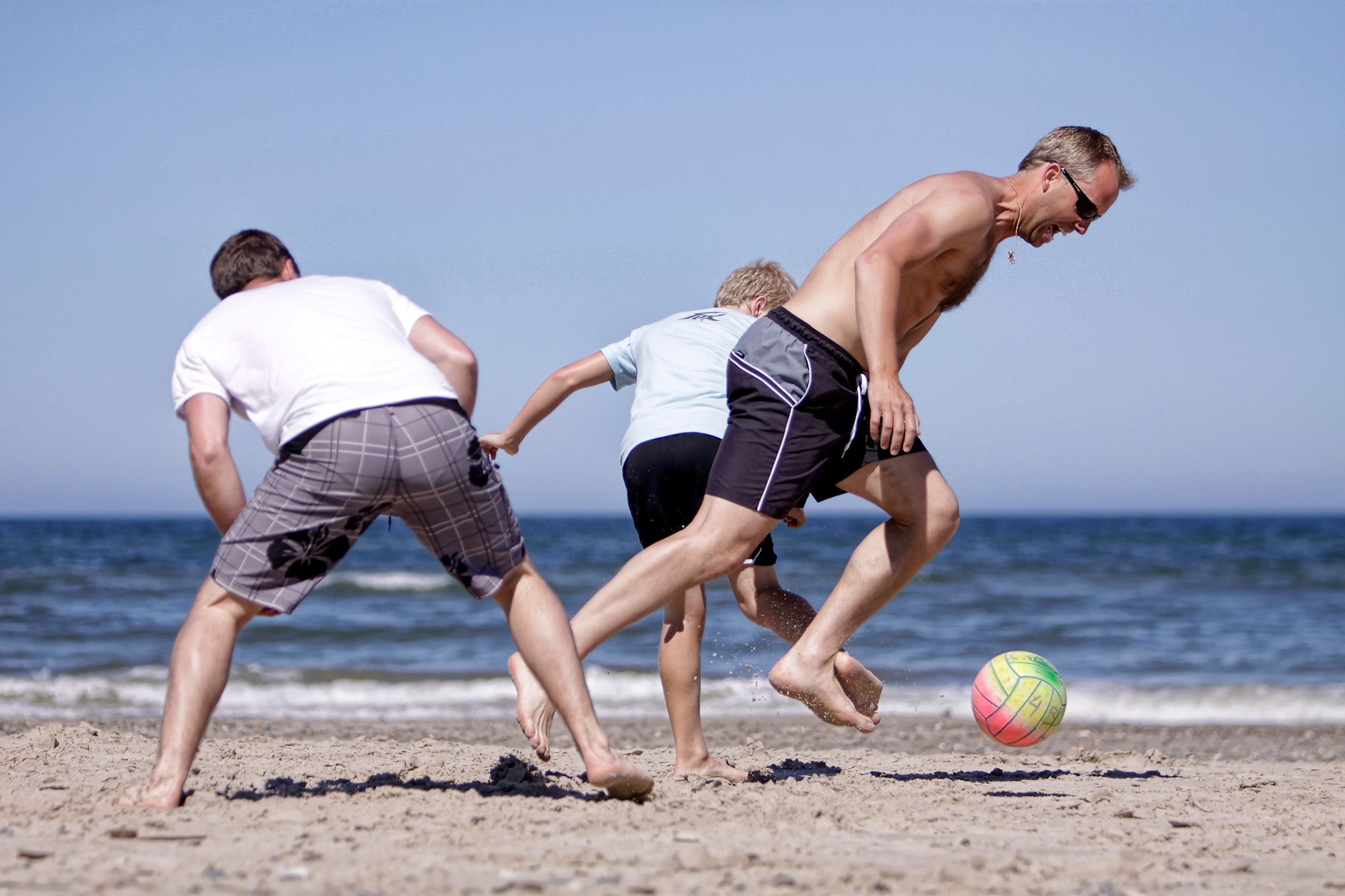 A lively game of beach soccer with family enjoying sunny weather.