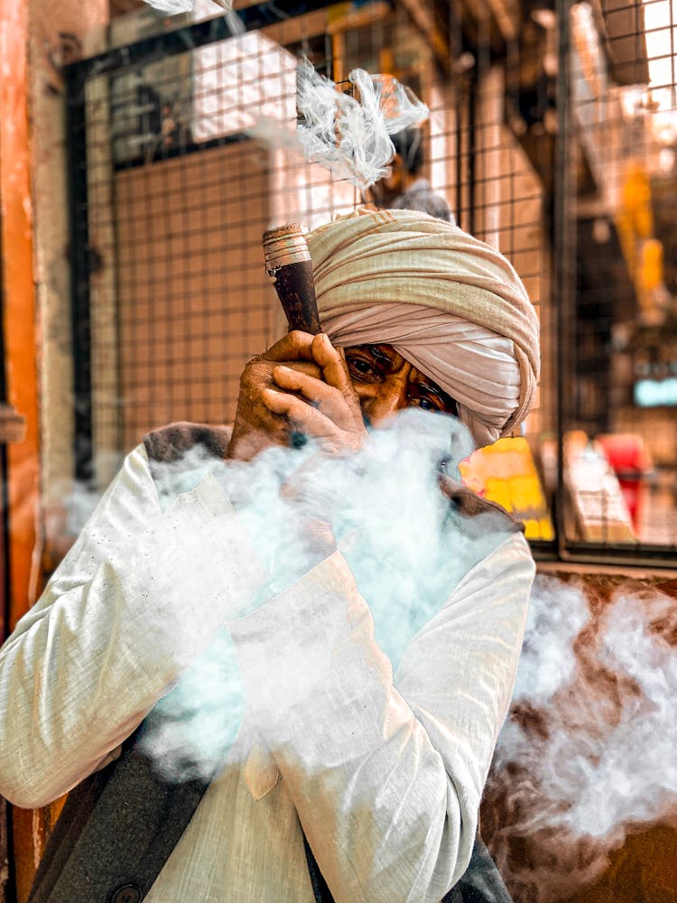 Old Man In Traditional Clothes Smoking Outdoors