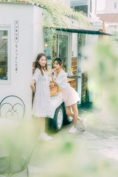 一位迷人的亚洲妇女站在街头植物丛中的小型餐车前