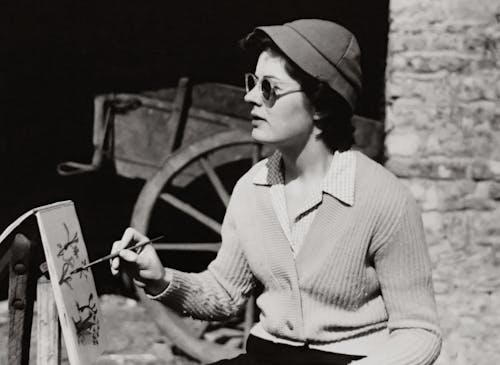 Woman in White Knitted Sweater and Black Hat Doing Painting Outdoors