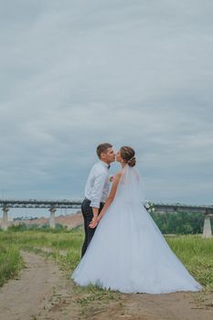 一对身着优雅服装的新婚夫妇，在光天化日之下站在人行道旁接吻的侧影
