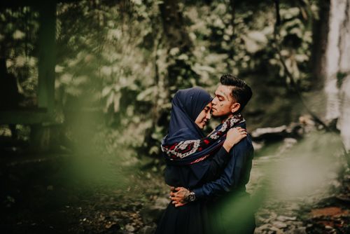 Free A couple shares a loving embrace in a lush green forest, surrounded by nature's beauty. Stock Photo