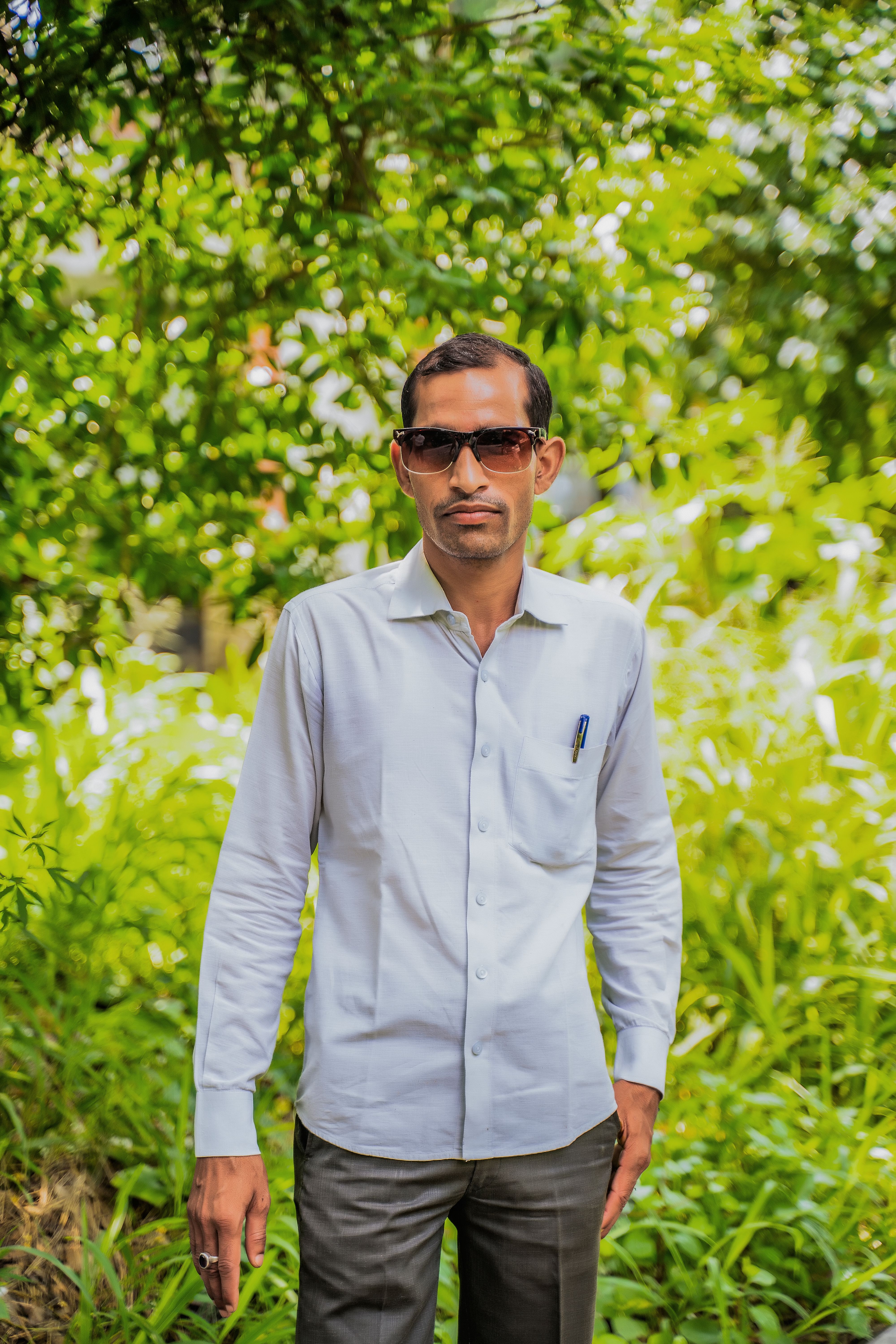 Portrait of a confident man standing outdoors wearing sunglasses.