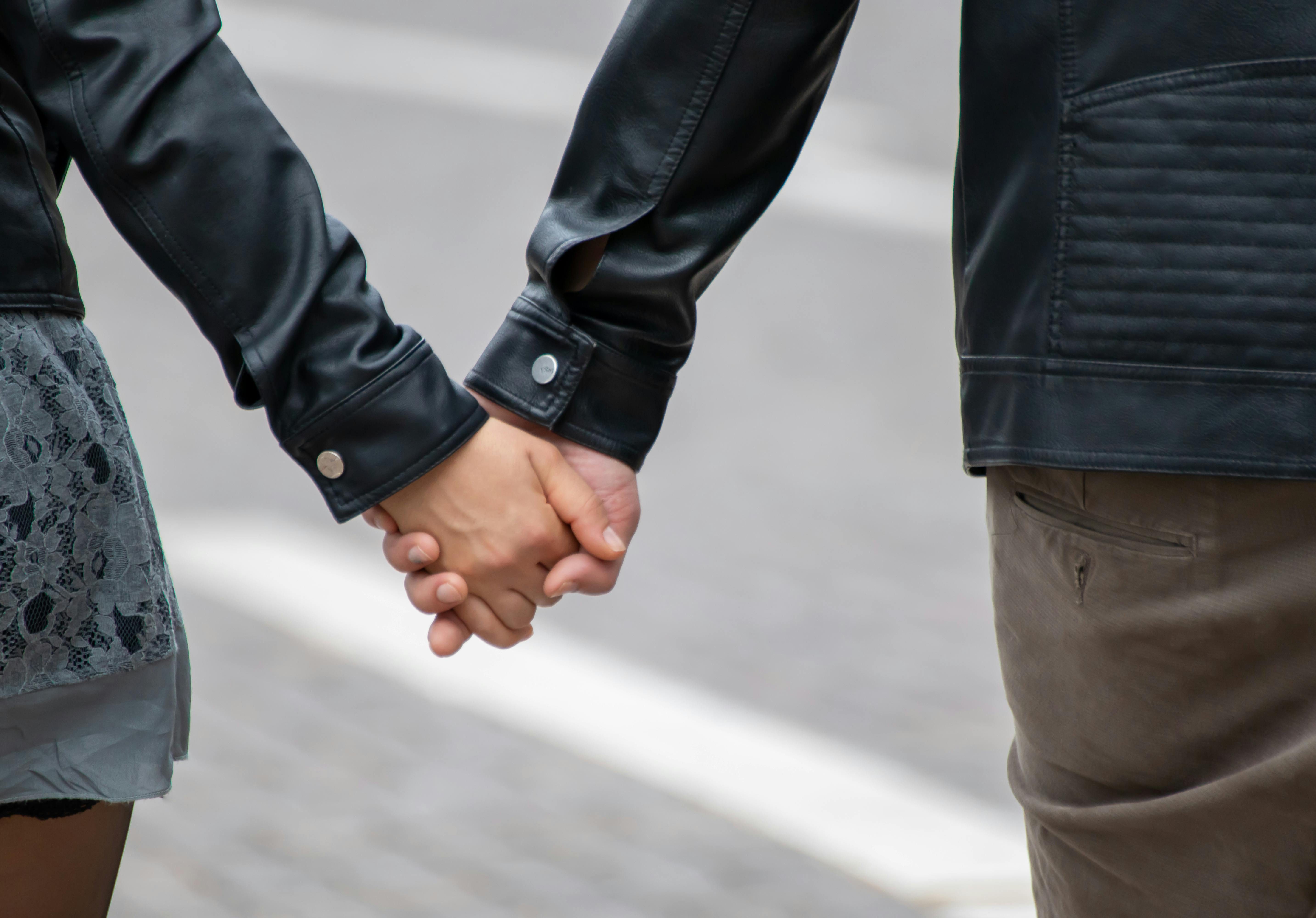 Person in Black Leather Jacket Holding Hands With Man in Black Leather