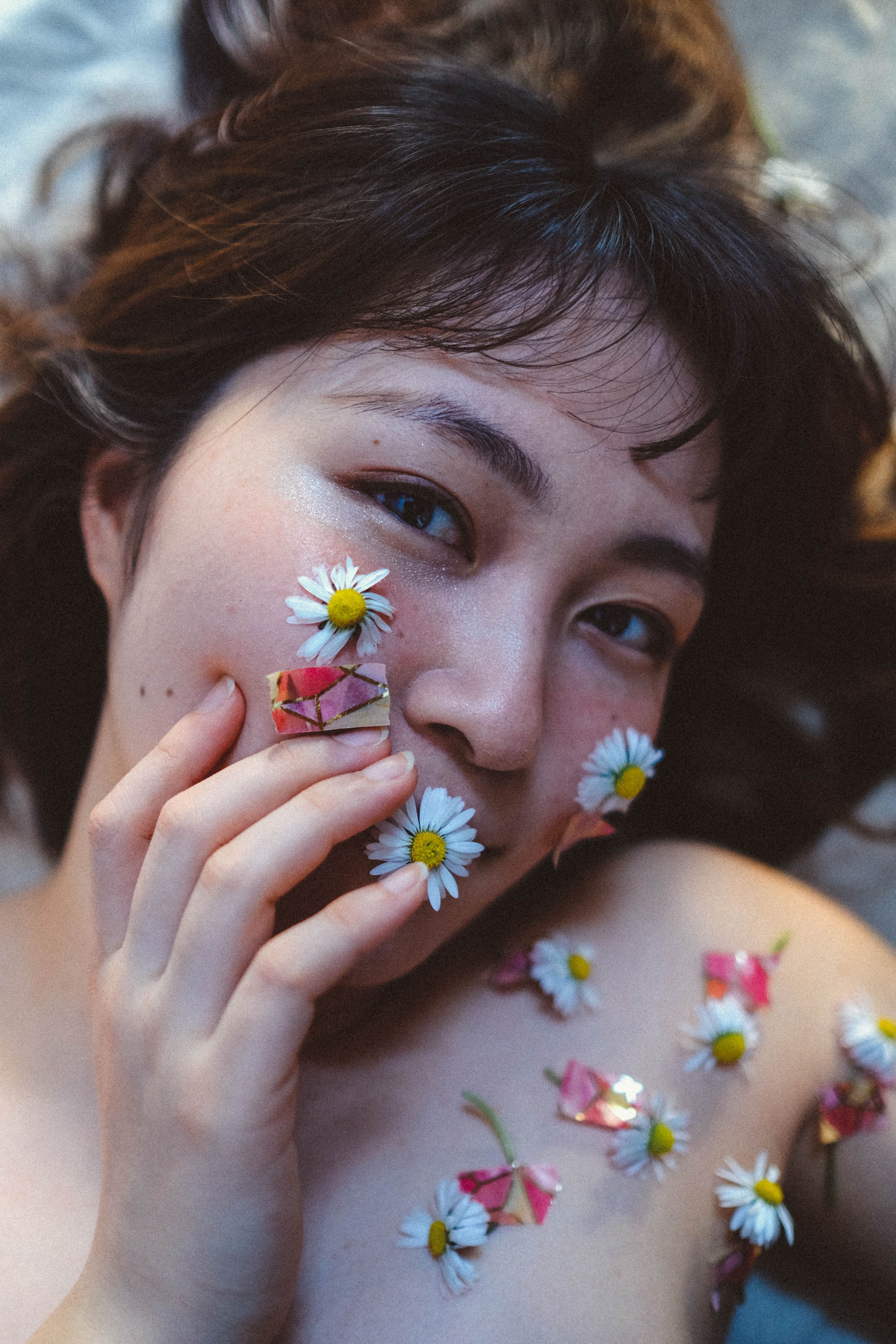 Artistic portrait of a woman with daisies and stickers enhancing a unique beauty concept