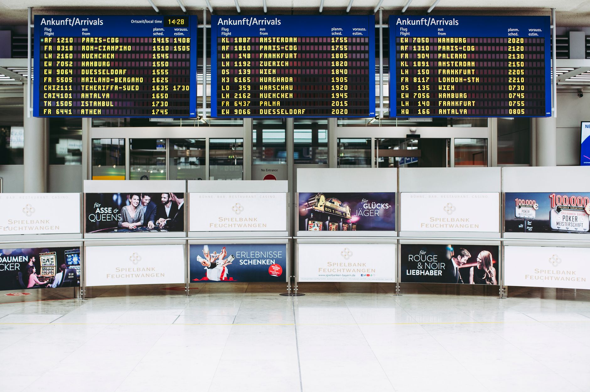 Electronic displays showing flight arrivals at Nuremberg Airport terminal.