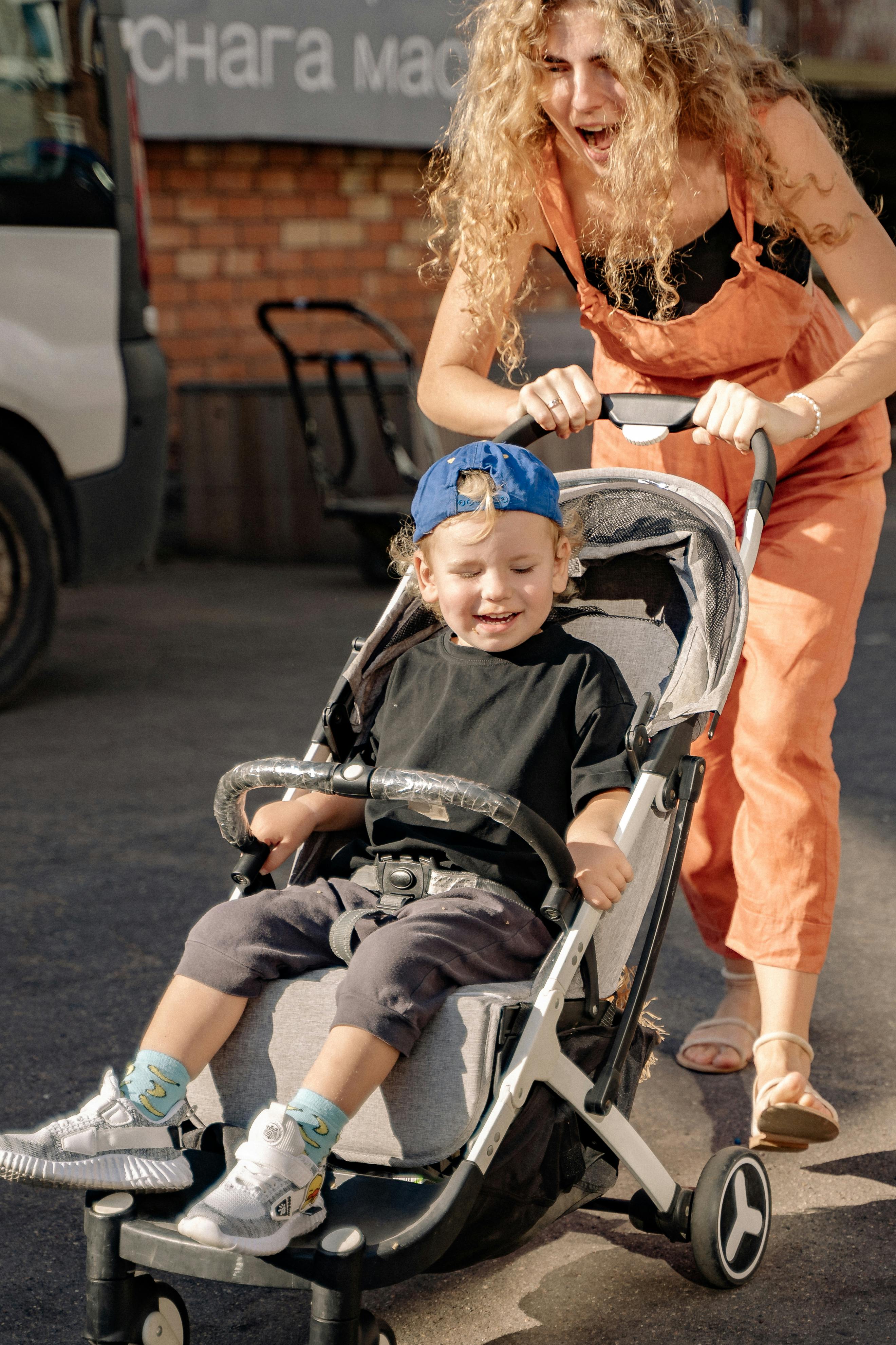 mother pushing a stroller with her son inside and smiling