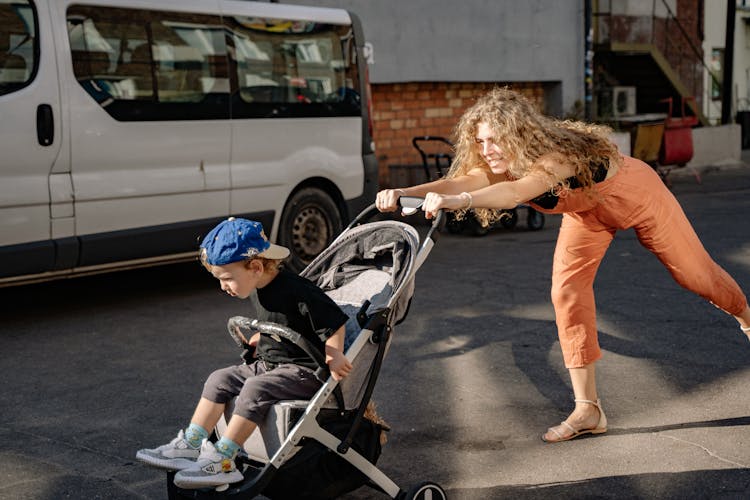 Mother Pushing Stroller With Son Through Stree