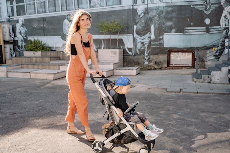 Mother Walking With Her Son In Stroller 