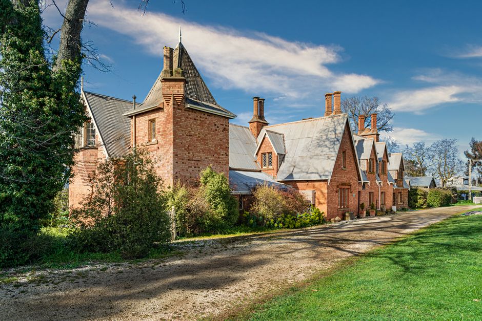 A charming historic brick building with manicured gardens under a clear blue sky in Campbell Town, Tasmania.