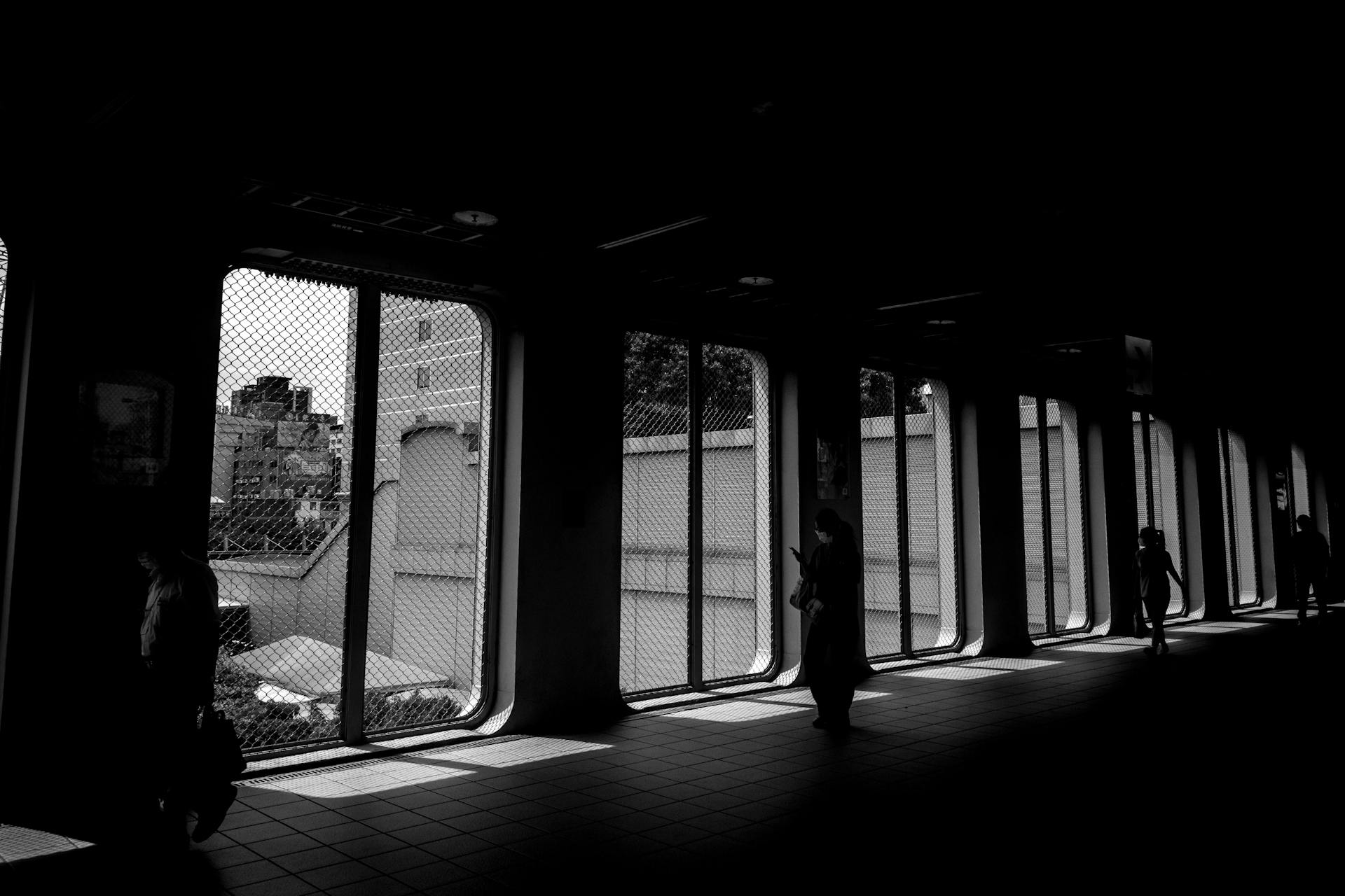 Black and white photo of a corridor with metal mesh windows and silhouettes of people in Taiwan.
