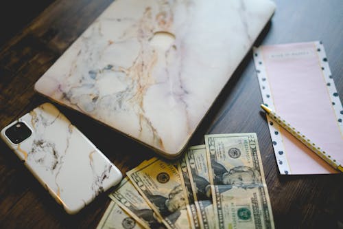 Free Gadgets and Cash on top of a Wooden Desk Stock Photo