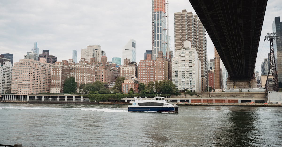 Modern boat floating on calm river channel near bridge in modern city in cloudy day