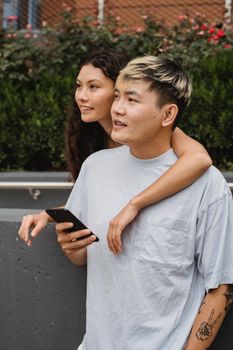 白天，一对穿着休闲装的多民族夫妇在街上快乐地拥抱，目光移开