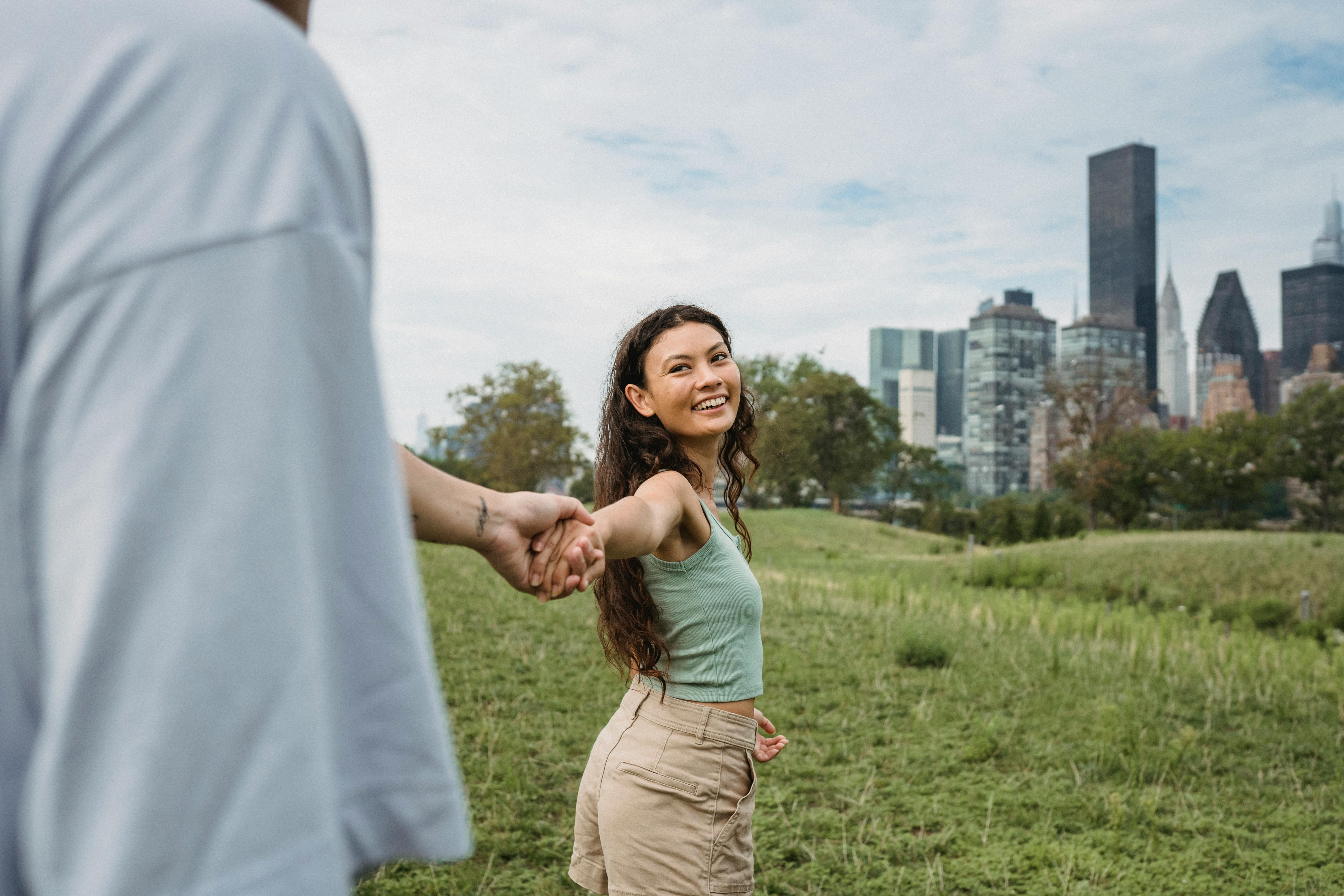 romantic young ethnic couple holding hands in city green park