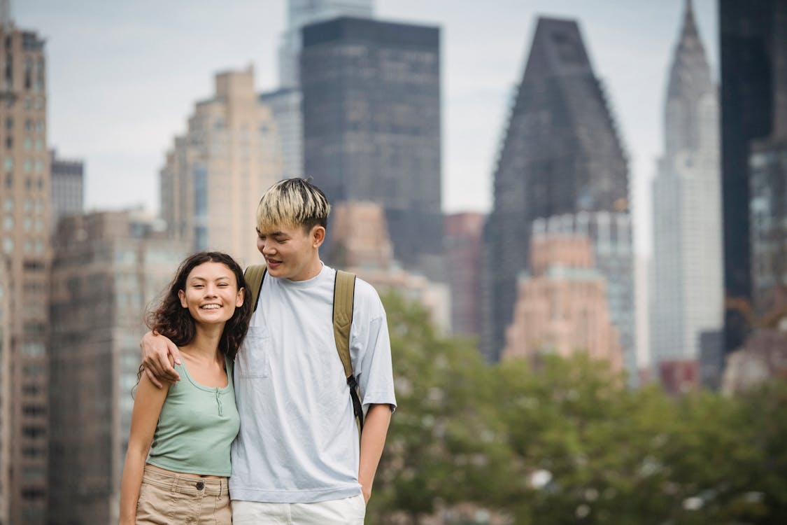 Delighted young ethnic couple cuddling while standing against scenic ...