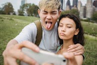 Crop diverse couple grimacing while taking selfie on smartphone