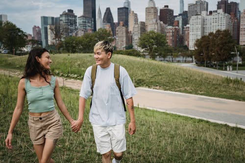 Pasangan Multietnis Yang Bahagia Berpegangan Tangan Di Padang Rumput Di Kota