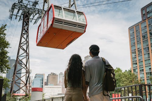 Anonymous couple contemplating cabin on ropeway in city