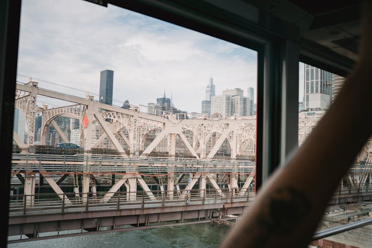 Crop Passenger In Cable Car Contemplating City Bridge Over River