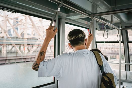 在河上旅行期间，一个留着现代发型、背着背包的匿名男性的背影，留在伴侣附近的电缆舱里
