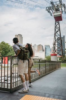 一对年轻夫妇从缆车站欣赏城市景观，享受城市郊游