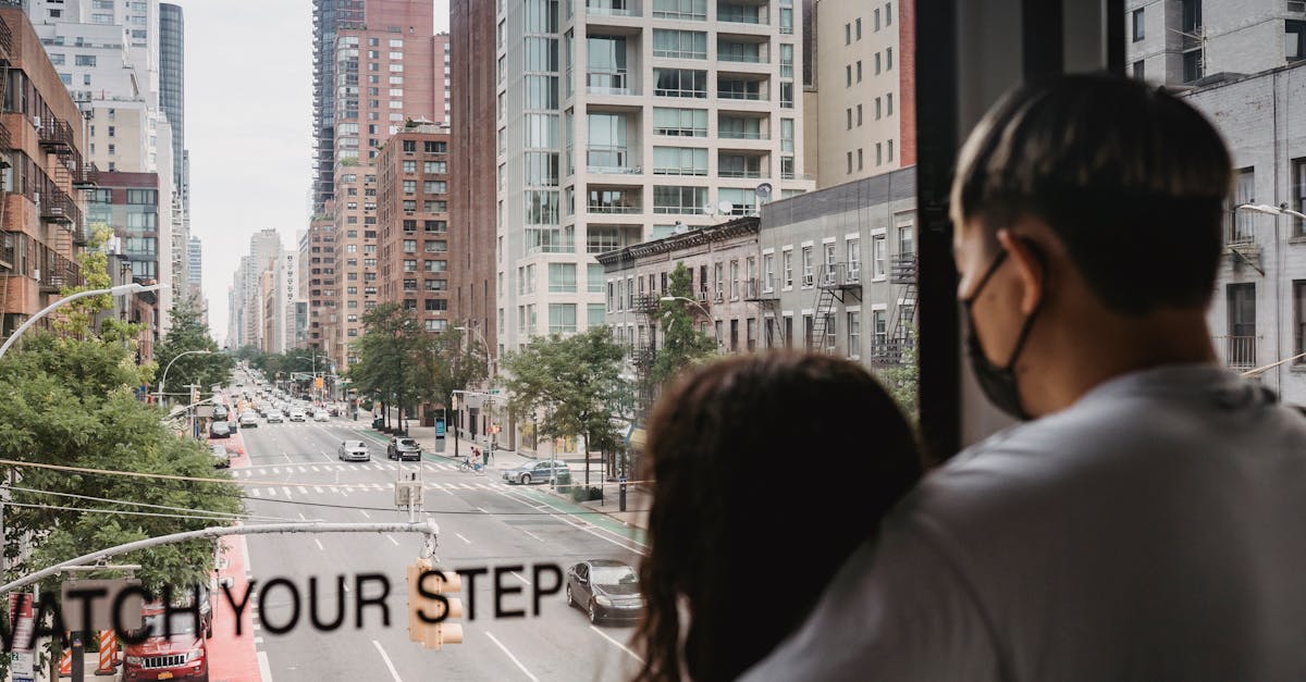 Back view anonymous romantic couple hugging and observing urban modern New York street while riding ropeway cabin