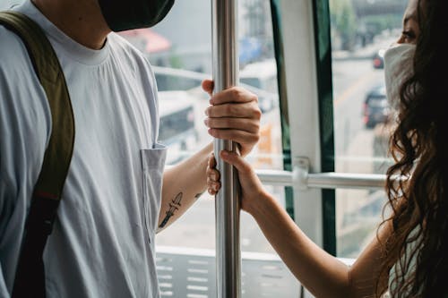 Crop couple in masks riding ropeway cabin in urban city