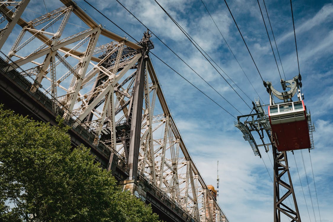 Low angle modern ropeway with observation cabin moving along cabin bridge against blue sky