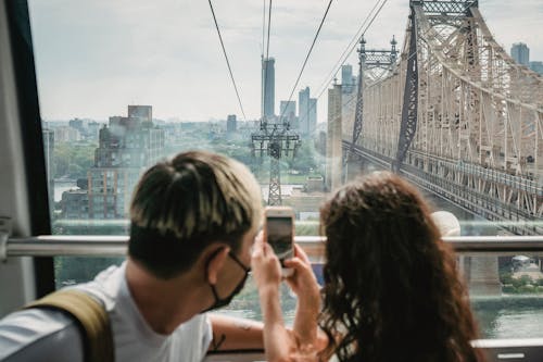 Unrecognizable couple riding ropeway cabin and taking photos of city