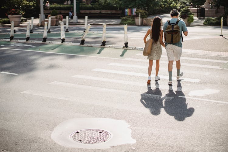 Unrecognizable Couple Crossing Road In Sunny City