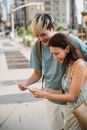 Cheerful diverse couple exploring map together while standing on street