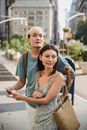 Positive multiracial couple checking direction in map while having trip together in city center