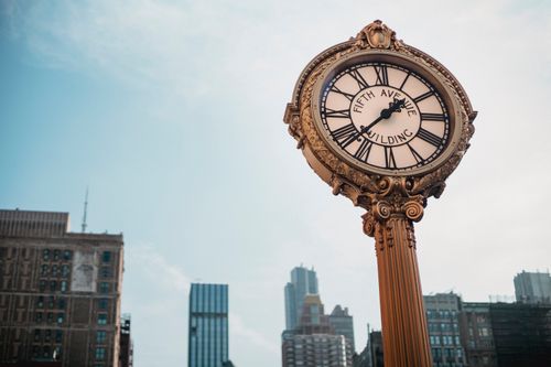 Free From below of aged metal clock tower located in city center with high towers Stock Photo