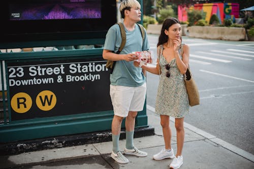 Full body of diverse couple standing with map while trying to find direction in city center during trip