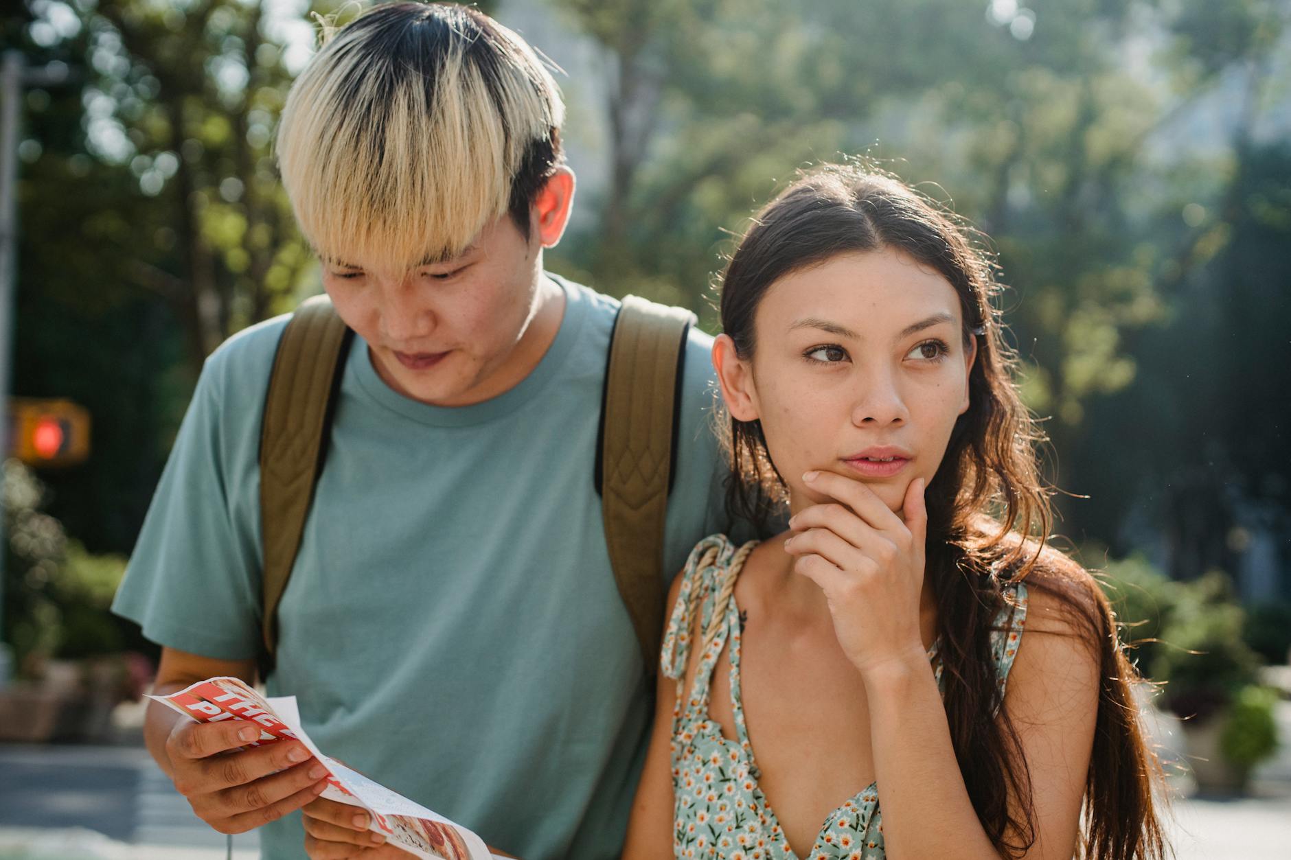 Confused multiracial couple searching way in map while discovering city together during summer holidays
